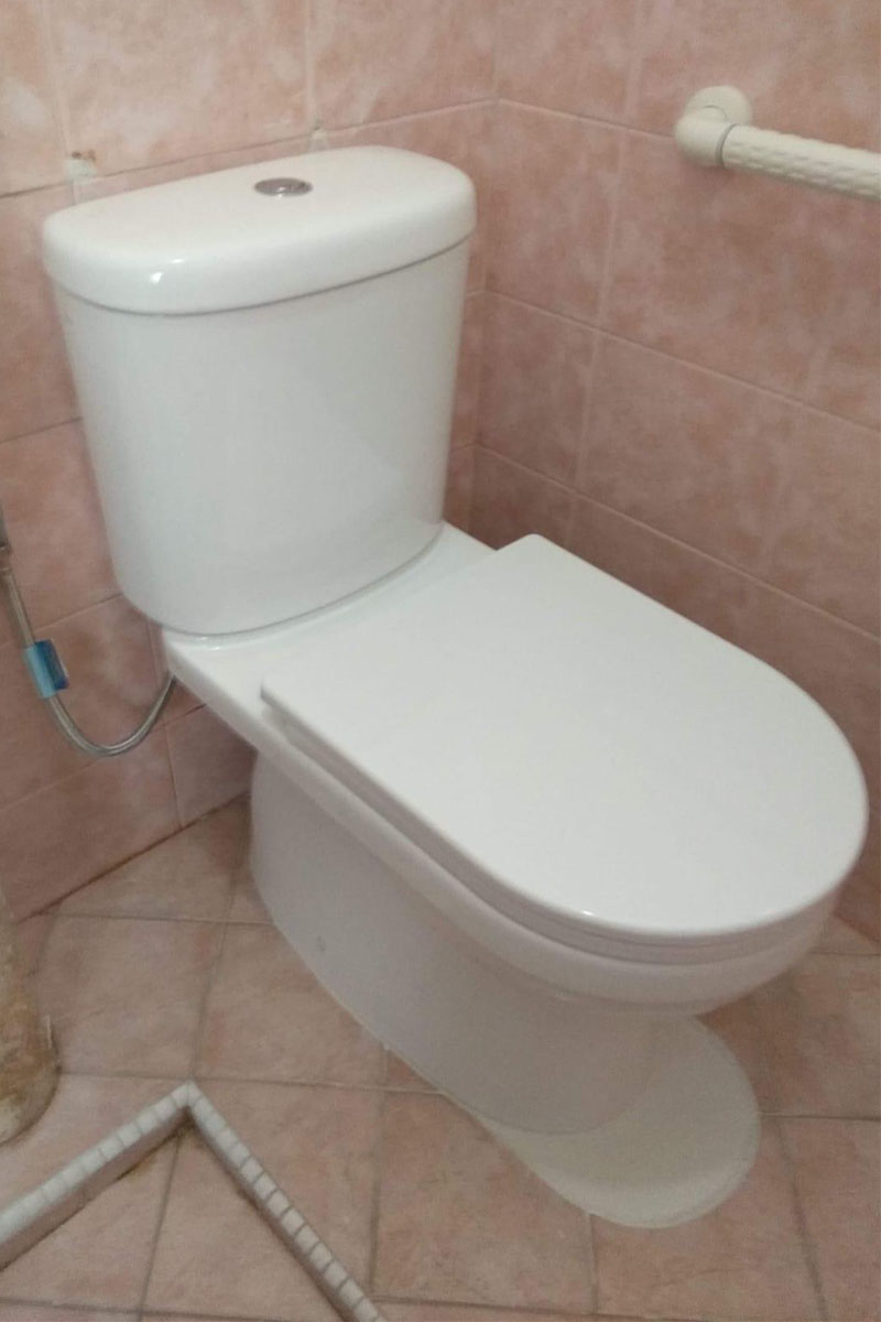 Plumber repairing a leaking toilet bowl in a Singapore HDB bathroom