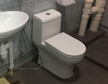 Plumber repairing a leaking toilet bowl in a Singapore HDB bathroom