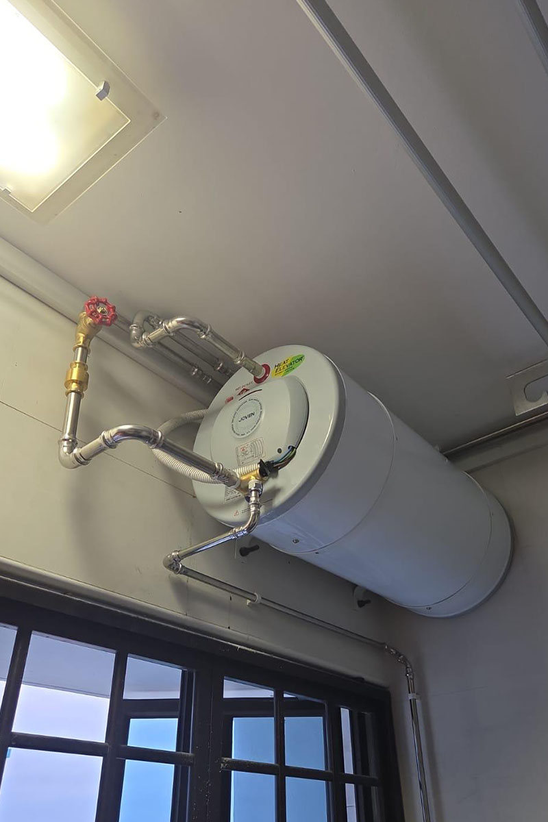 Plumber repairing a faulty water heater in a Singapore HDB bathroom