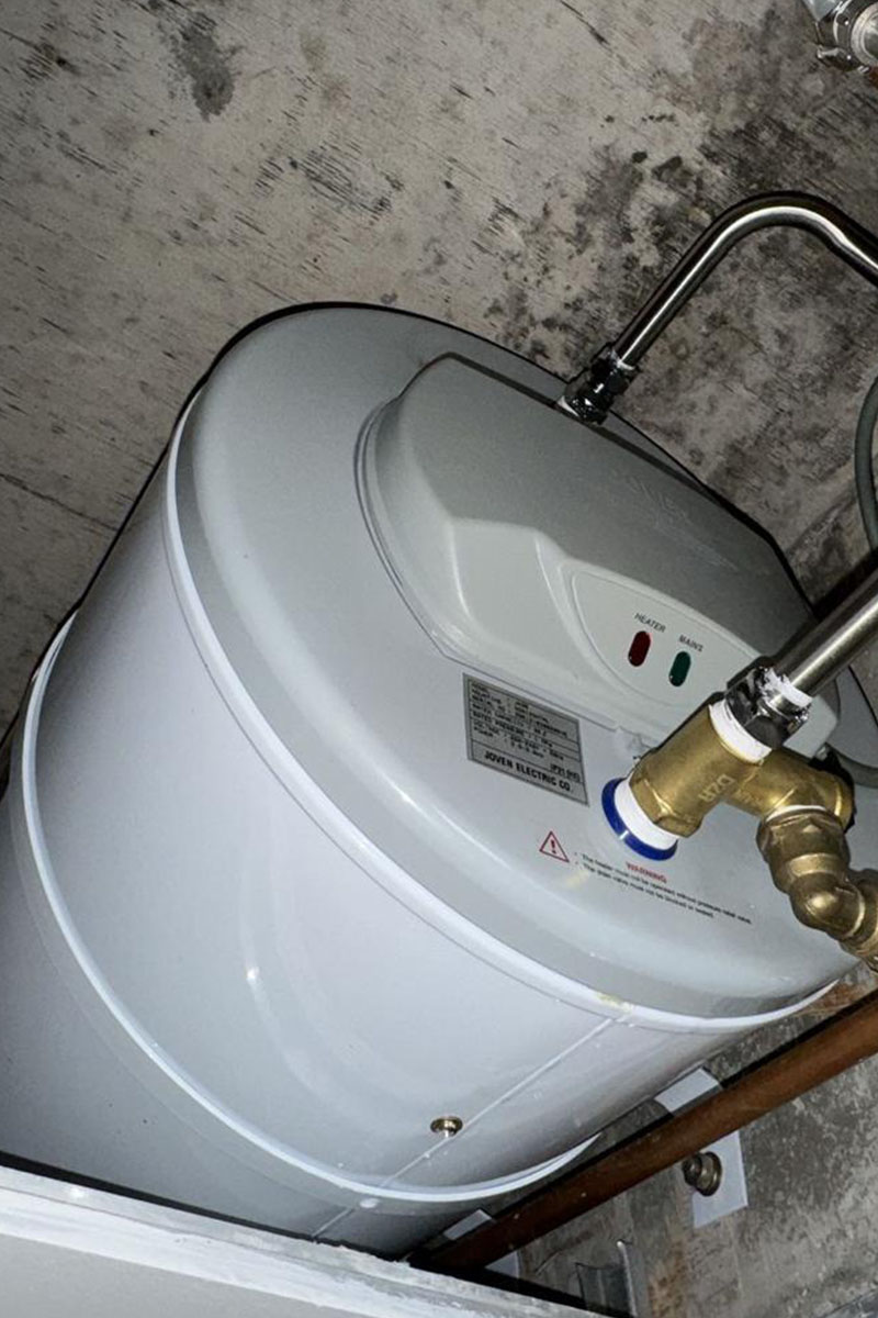 Plumber repairing a faulty water heater in a Singapore HDB bathroom