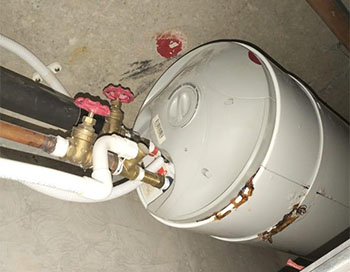 Plumber repairing a faulty water heater in a Singapore HDB bathroom